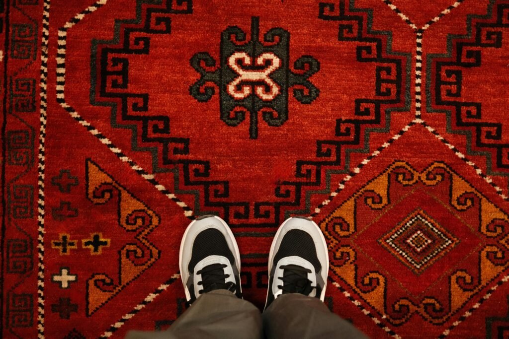 A pair of sneakers standing on a vibrant traditional red carpet in Kazakhstan.